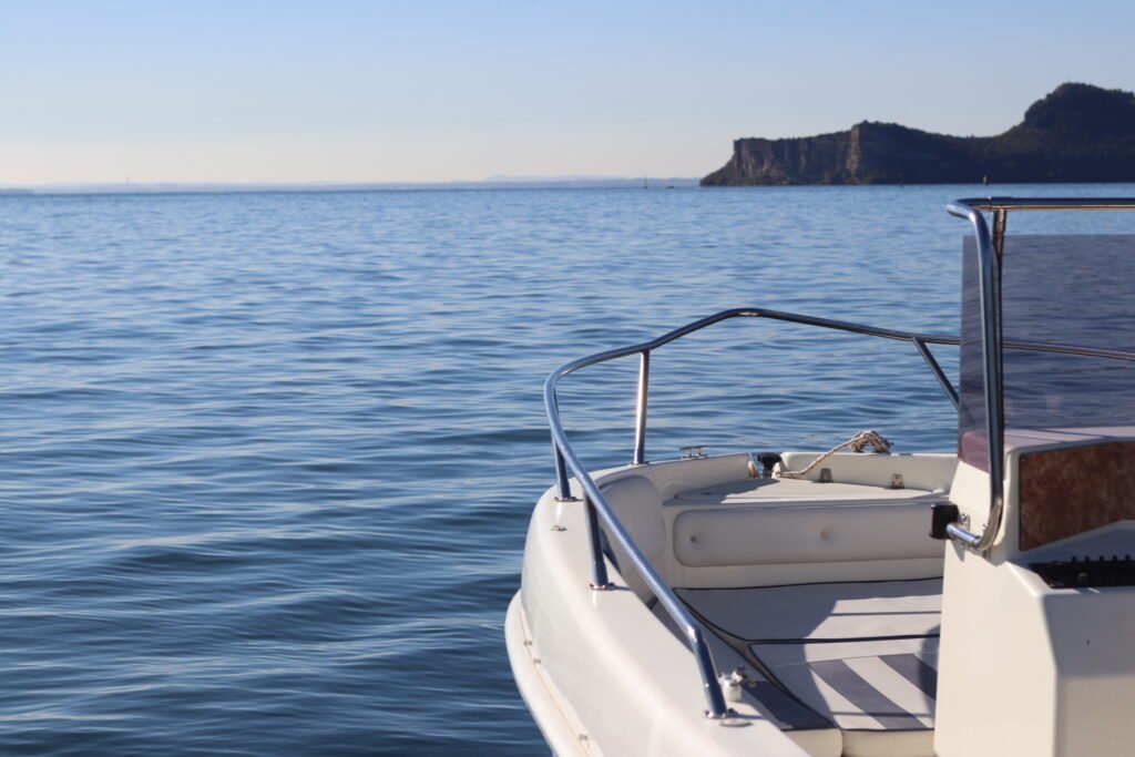 Prua di una barca con vista sul lago e costa rocciosa all’orizzonte.